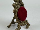 brass figurine of a cheren with a red velvet cushion