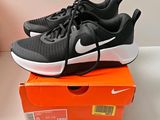des chaussures de course Nike noires et blanches posées sur une boîte orange