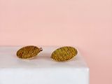 un gros plan sur une paire de boucles d'oreilles en or posées sur un bloc de marbre