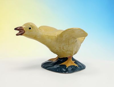 yellow duck figurine with open beak on blue and yellow background