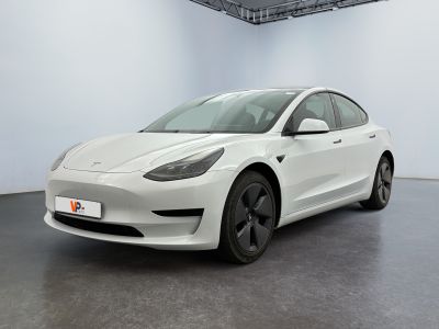 une Tesla Model 3 blanche garée dans une pièce blanche