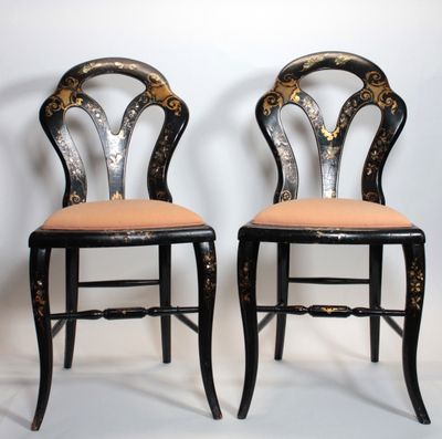une paire de chaises peintes en noir et or, posées contre un mur blanc