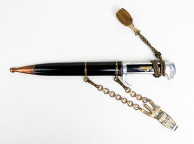 un stylo muni d'une chaîne, posé sur une surface blanche
