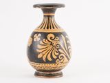 a black and gold vase sitting on a white surface