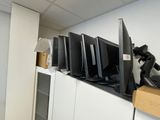 many computer monitors on a shelf in a room