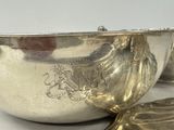 a silver bowl and a silver spoon on a white table