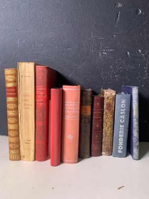de nombreux livres anciens alignés sur une étagère près d'un mur noir
