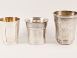 three silver cups are lined up next to each other on a white surface