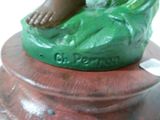 une statue représentant une personne assise sur un objet vert