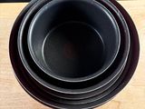 une pile de trois bols noirs posée sur une table en bois
