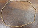 a close up of a gold necklace on a wooden table