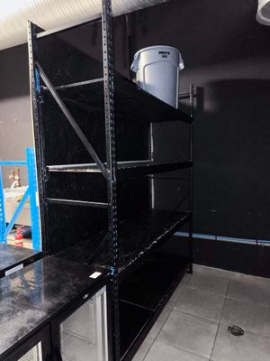 une étagère noire au milieu d'une pièce, sur laquelle se trouve un seau