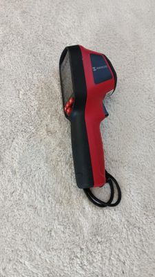 an infrared thermometer is laying on the floor next to a cord