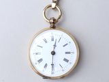 une petite montre de poche en or avec des chiffres romains