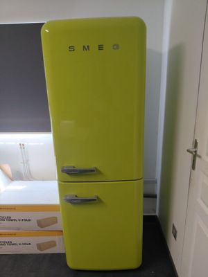 un réfrigérateur vert citron dans un coin d'une pièce, avec une baignoire blanche en arrière-plan