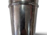 une tasse en argent posée sur une surface blanche