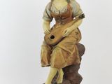 figurine of a woman sitting on a rock with a guitar