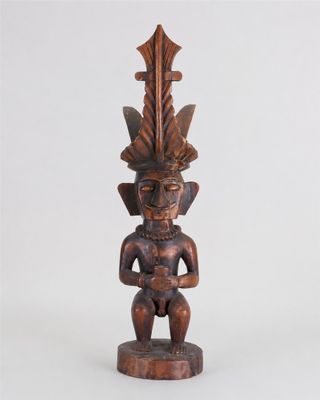 une statue en bois représentant un homme avec une plume sur la tête