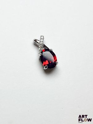 une image représentant un pendentif orné d'une pierre rouge sur fond blanc