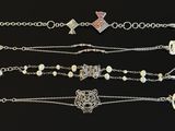 five different bracelets with tags and charms on a black background