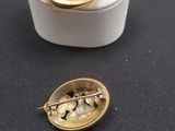 a small white box with a gold broocher and a pair of pins