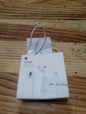 Des écouteurs Apple Earpods sont posés sur une boîte, elle-même posée sur une table en bois.