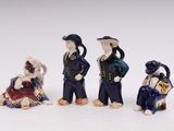 four ceramic figurines of people sitting on a white surface