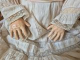 a close up of a doll ' s hands on a dress