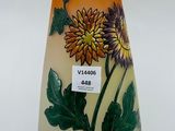 un vase avec des fleurs peintes dessus, posé sur une table