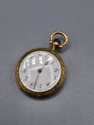 une montre de poche en or avec un cadran blanc sur un fond gris