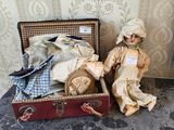 une poupée assise dans une valise à côté d'une autre poupée