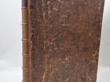 an old book with a brown cover sitting on top of a white surface