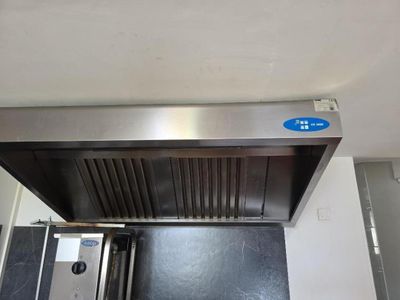 une hotte en acier inoxydable dans une cuisine, sur laquelle est collé un autocollant bleu