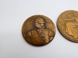 deux médaillons en bronze représentant un homme et une femme sur un fond blanc