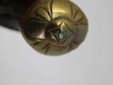 a hand holding a pen with a gold ball on it