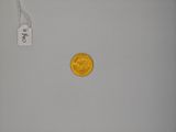 a gold coin on a white surface with a price tag on it