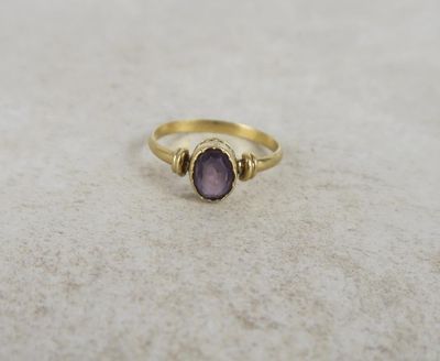 a close up of a gold ring with a purple stone