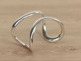 silver plated open ring with curved design on a wooden surface