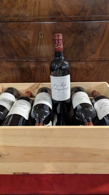 des bouteilles de vin dans une caisse en bois posée sur une nappe rouge