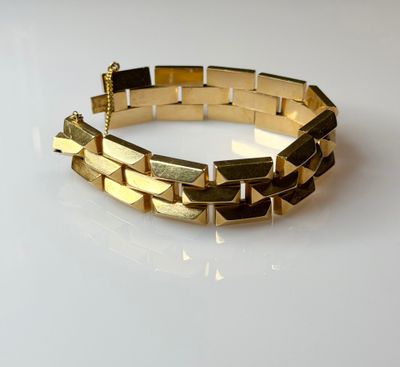 a close up of a gold bracelet on a white surface