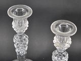 two clear glass candlesticks sitting on top of a black table