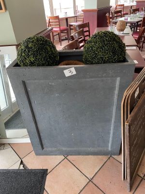 tables and chairs in a restaurant with a large planter on the floor