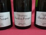 trois bouteilles de vin sont alignées sur un support rose