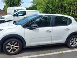 a white car parked in a parking lot next to some bushes