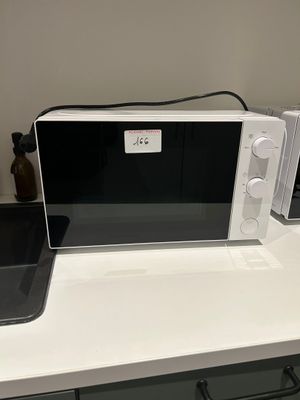 un micro-ondes blanc posé sur un plan de travail, à côté d'un téléphone portable