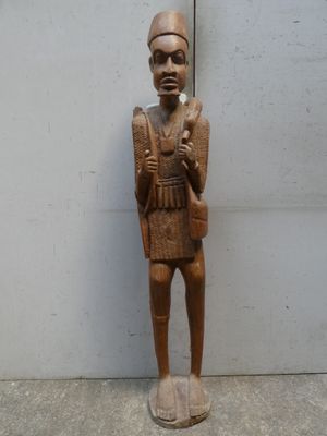 statue en bois représentant un homme tenant un couteau dans chaque main