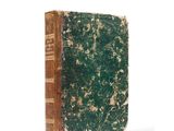 an old book with a green cover sitting on a white surface