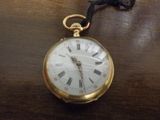 une montre de poche en or, ornée de chiffres romains, posée sur une table