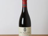 a bottle of red wine sitting on top of a wooden table