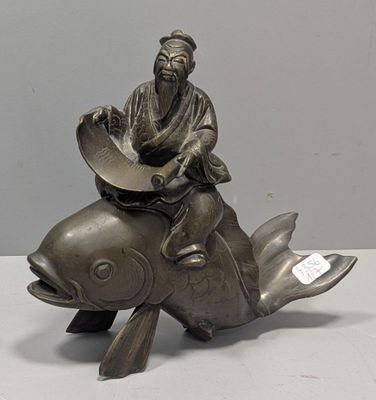 une statue représentant un homme assis sur un poisson